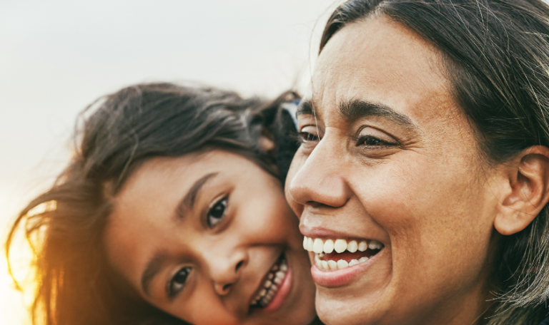 Close-up of a happy mother and daughter having a tender moment and embracing each other at the beach.